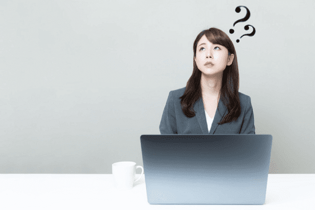 パソコンを前に疑問を浮かべる人の画像