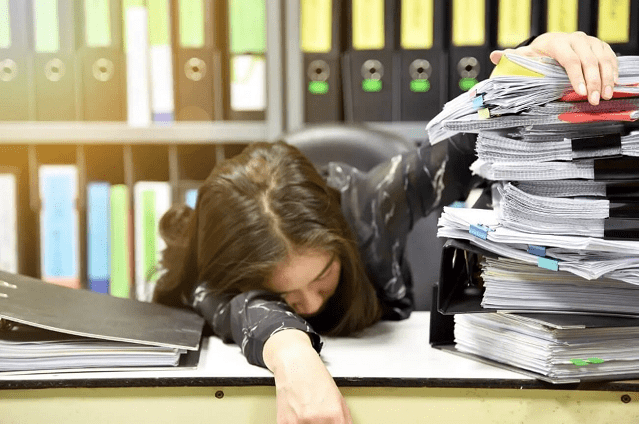 書類の中で居眠りする人の画像