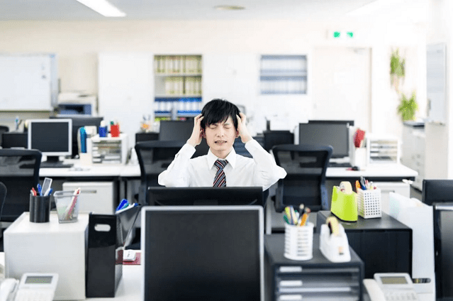 会社で頭を抱える男性の画像